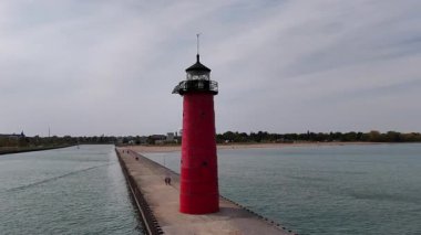 Kenosha Deniz Feneri Stüdyosu Kırmızı Feneri, sakin bir iskelede, bulutlu bir gökyüzü, küçük bir kasaba ve sahil yakınında. Kenosha, Wisconsin, Amerika Birleşik Devletleri.