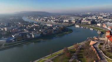 Vistula Nehri 'nin hava manzarası güneşli bir günde şehir binaları ve yeşil setlerle Polonya' nın Krakow kentinden akıyor.