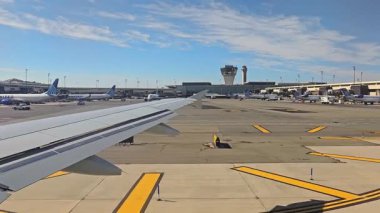 New Jersey 03.03 2025 Yoğun bir havaalanı taksiyolundaki uçak penceresinden görüntüleme, birçok United Airlines uçağı kapılara park edilmiş, kontrol kuleleri operasyonları denetleme, ve açık mavi bir gökyüzü oluşturma