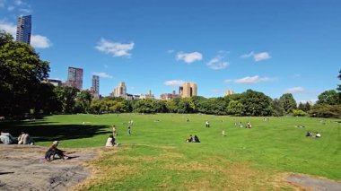 - New York. Biziz. 03.03.2025 Central Park Koyun Çayırı güneşli bir günde arka planda Manhattan silueti olan yeşil çimlerde dinlenen insanlar şehir yaşamını doğal sükunetle harmanlıyor.