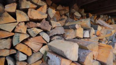 Depoda düzgünce istiflenmiş odun yığınları doğal dokular, sert kabuklar ve kış ısıtması için odun yüzeyleri sergiliyor.