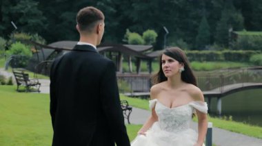 Gelin ve damat açık havada romantik bir düğün ortamında, manzaralı bahçe köprüsünün yanında zarif bir an, aşk ve duygular zamansız bir düğün portresinde yer alıyor.