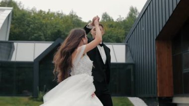 Modern mekanda romantik düğün dansı, zarif gelin ve damat aşkı kutluyor, çağdaş mimariyle büyülü açık hava anı