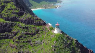 Hawaii 'nin güneydoğu kıyısındaki Oahu' nun turkuaz sularının üzerindeki yemyeşil bir uçuruma tünemiş Makapuu Deniz fenerinin hava manzarası..