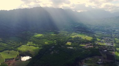 Hawaii 'deki yemyeşil vadi ve dağların havadan görünüşü dramatik dağ sırtlarıyla çevrili yeşil Hawaii vadisinde güneş ışığı bulutları delip geçiyor..
