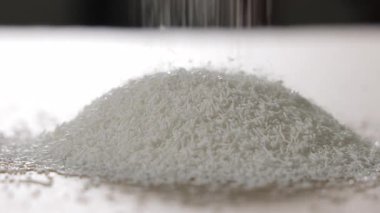 Beyaz plastik granüller, parlak bir endüstriyel ortamda büyüyen bir yığın üzerine düşüyor, enjeksiyon kalıplarında ya da bileşen imalatında kullanılan ham polimer materyallerin yakın çekimi