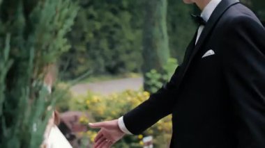 Gelin ve damat bahçede hassas bir anı paylaşıyorlar, romantik düğün portresi çekilirken gülümsüyorlar ve yakınlaşıyorlar..