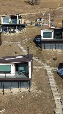 Geniş cam pencereli modern yamaç kulübeleri, uzak bir kırsal alanda inşa halindeki vadinin panoramik manzarasını sunuyor, doğayı çağdaş tasarımla harmanlıyor.