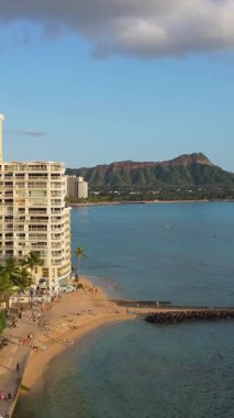 Okyanus manzaralı Honolulu silueti. Arka planda altın kum, palmiye ağaçları ve Diamond Head Dağı olan DeRussy Kalesi..