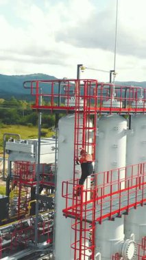 Hava gözlem istasyonu operatörü istasyonun tepesinden iniyor. Dağlardaki modern gaz kompleksi. Gaz işçisi, gaz dağıtım ünitesinin merdivenini tırmanır, dağ zeminine karşı.