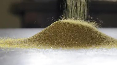 Ağır çekimde düşen altın yıpratıcı tanecikler endüstriyel materyalin hareketli makro görüntüsü.