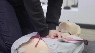 Kukla üzerinde suni teneffüs uygulaması yapan eller, tekniğe odaklanmış ilk yardım eğitimi..