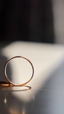 Sunlight 'taki nikah yüzüklerinin yakın çekimi. Düz bir yüzeyde, pencereden süzülen güneş ışığıyla güzelce aydınlatılan üç alyansın yakın plan çekimi.