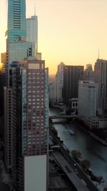 Gün batımında nehir manzaralı Chicago silueti. Şikago 'nun gün batımında gökdelenlerin altın ışığı yansıtan, Chicago Nehri' nin çarpıcı manzarası.