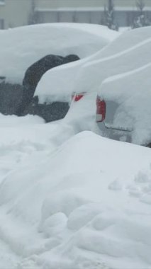 Bir adam arabasını kardan temizler. Bir kürekle kardan kar için otoparkı temizliyorum.