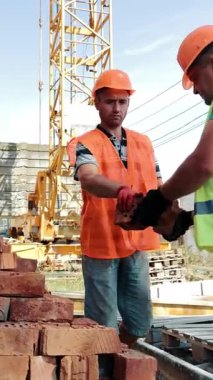 İnşaatçılar tuğla yüklüyor. Erkek İşçiler Tuğlaların Parçalanması Arasında Sıralanır.