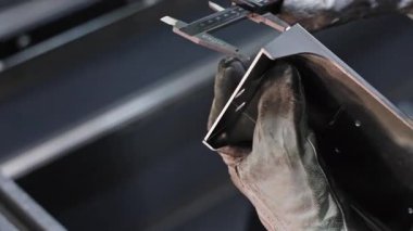 Metal bileşenlerini dijital kalibreli ölçen eldivenli işçi, endüstriyel ortamdaki hassas mühendislik süreci.