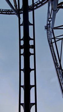 Aşağıdan bakıldığında lunapark trenlerinin, karanlık metal rayların ve hareket eden arabaların dramatik alçak açılı görüntüsü.