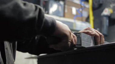 İşçi atölyede alüminyum profil dosyalama, hassasiyet montajı için mekanik metal parçaların elle bitirme işlemi.