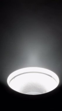 Tavan lambasının aydınlatması karanlık bir odada, tavan lambasının yakın çekimi karanlık bir uzayda parlak ışınlar yayıyor.