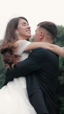Gelin ve damat parkta dans ediyorlar. Damat gelini kucağına aldı ve dans ederken döndürdü..