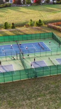 Pickleball Sahalarının Hava Görüntüsü, Pickleball sahalarının yeşil eskrim ve açık alanlarla çevrili oyuncularla oynanan dış top sahalarının drone çekimi