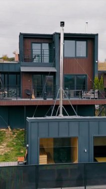 Modern Hillside Home with Balconies ve Patio Space. Ahşap ve metal aksanları, geniş balkonları, teras alanı ve çatı salonu olan çok katlı bir tasarımı olan çağdaş bir dağ evi.