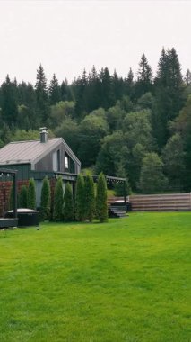 Geniş Çim ve Orman Manzaralı Modern Kulübeler. Pürüzsüz tasarımları ve yeşil metal çatıları olan iki modern kulübe, yoğun orman destekli, çitlerle çevrili geniş bir çimenliğe kurulmuş.