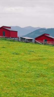 Dağların arka planında iki kırmızı evi olan gökyüzü manzaralı bir dağ manzarası. Dağlarda ahşaptan yapılmış ahşap ekolojik evler.