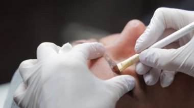 Güzellik salonunda kaş mikroplu pateni, güzellik uzmanının hassas bir aletle pigmenti sürmesi, kozmetik kaş geliştirme sürecinin yakın çekim görüntüsü.