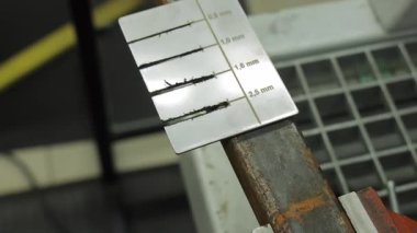 Kaynak göstergesi metaldeki boncuk boyutunu ölçüyor. Kalite kontrol sürecinde paslı bir çelik çubuğun üzerindeki boncuk genişliğini ölçmek için kullanılan kaynak göstergesi aracının yakın plan görüntüsü
