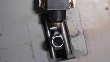 Lazer kesme makinesi metal boruyu işliyor. Lazer kesici bir kafanın yakın çekim görüntüsü yuvarlak metal bir tüp kesmek için hizalanmış, endüstriyel bir hassasiyeti var.
