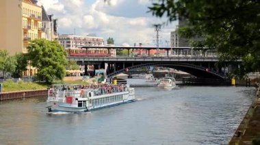 Berlin Almanya 25.05.2025, Turist Teknesi Spree Nehri Berlin 'de Şehir Treni Köprüsü' nden ve Arka plandaki Tarihi Kubbe 'den geçiyor.