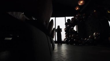 Akşam Vakti Penceresinde Duran Kadın Silueti, Loş Kapalı Salon Salonu 'nda Loş Işıklı Siyah ve Altın Balon Kemeri ve Zarif Atmosferde Yansıtıcı Zemin.