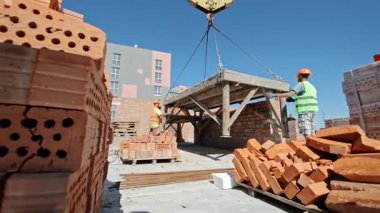 İnşaat İşçileri Askıya Alınan Platformu, Tuğla Yığını ve Malzemeleri Çevreleme Etkin Çalışma Alanını Konumlandırıyor.