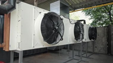 Endüstriyel havalandırma vantilatörlü kondansatör üniteleri. Güçlü havalandırma vantilatörleriyle donatılmış büyük ticari HVAC yoğunlaştırıcı üniteleri iklim kontrolü için kapalı bir alana yerleştirildi..