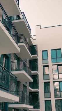 Modern, yüksek katlı bir binanın dışı. Pencereleri ve geniş balkonları olan çok katlı modern bir bina..