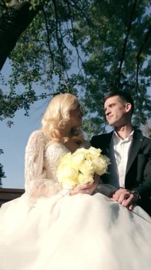 Parktaki bir bankta, damat ve gelin birlikte oturuyorlar. Autumn Park 'ta güzel bir sonbahar sabahı.