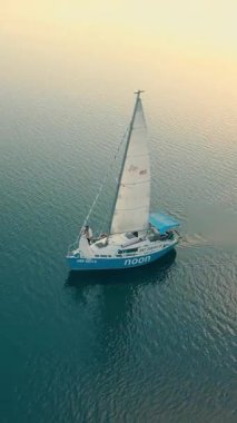 Ukrayna. Lviv. 19.09.2020. Günbatımında bir yatın hava aracı görüntüsü, gökyüzü yansımalarıyla parlayan su. Kamera, sessiz denizin üstündeki yelkenin yanında uçuyor..