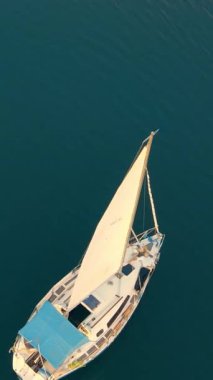 Ukrayna. Lviv. 19.09.2020. İnsansız hava aracı günbatımında sakin suda huzurlu bir yat yakalar. Güneş denizin ve yumuşak bulutların ardında batarken yelken gökyüzünü yansıtıyor..