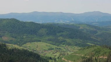 Ormanı ve kırsal köyü olan dağ vadisi. Ağaçlarla ve orman kaplı tepelerle çevrili küçük kırsal evlerle dolu yemyeşil bir dağ vadisini geniş açıdan görebiliriz.