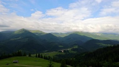 Bulutlar dağ vadisine gölge düşürüyor. Yeşil bir dağ manzarasında sürüklenen dramatik bulutların hızlandırılmış videosu, tepeler ve ormanlar üzerinde hareket eden gölgeler oluşturuyor.