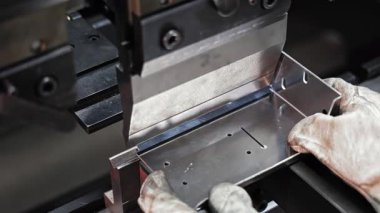 Hidrolik baskı ile metal bükme. Metal işçisinin hidrolik baskı fren makinesini kullanarak metal levhayı düzgün açılara ve şekillere çevirdiği yakın plan.