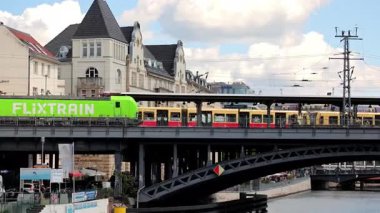 Berlin Almanya 25.05.2025: FlixTrain Yeşil Lokomotif ve Friedrichstrasse İstasyonu 'ndaki Sarı S Bahn Demiryolu Köprüsü Tarihi Binalar, şehir ulaşımı ve seyahati.
