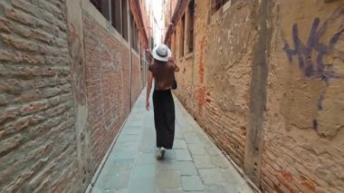 Beyaz Şapkalı Kadın Dar Geçitte Tuğla Duvarlar ve Graffiti ile Yürüyor Eski Şehir Sokaklarında Yaz Keşfi Atmosferi.