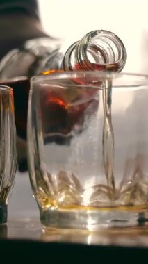 Viski kadehi zarifçe bardağa dökülüyor. Viski kadehi zarifçe bardağa dökülüyor. Temiz bir bardağa dökülen kehribar viskisinin yakın çekimi.