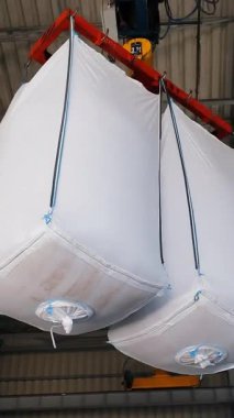 Endüstriyel Toptan Çantalar Depo, Beyaz 'da askıya alındı. Malzemelerle dolu, endüstriyel bir depoda asılı.