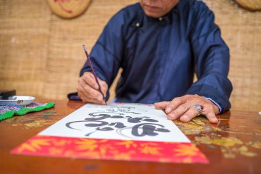 Ao Dai giyen Vietnamlı bilgin yazı yazıyor. Kaligrafi festivali Tet bayramında popüler bir gelenektir. Bahar Festivali için çiftler yazma, yeni yıl.