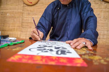 Ao Dai giyen Vietnamlı bilgin yazı yazıyor. Kaligrafi festivali Tet bayramında popüler bir gelenektir. Bahar Festivali için çiftler yazma, yeni yıl.