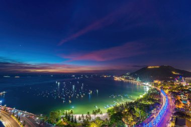 Vung Tau city aerial view with beautiful sunset and so many boats. Panoramic coastal Vung Tau view from above, with waves, coastline, streets, coconut trees and Tao Phung mountain in Vietnam.